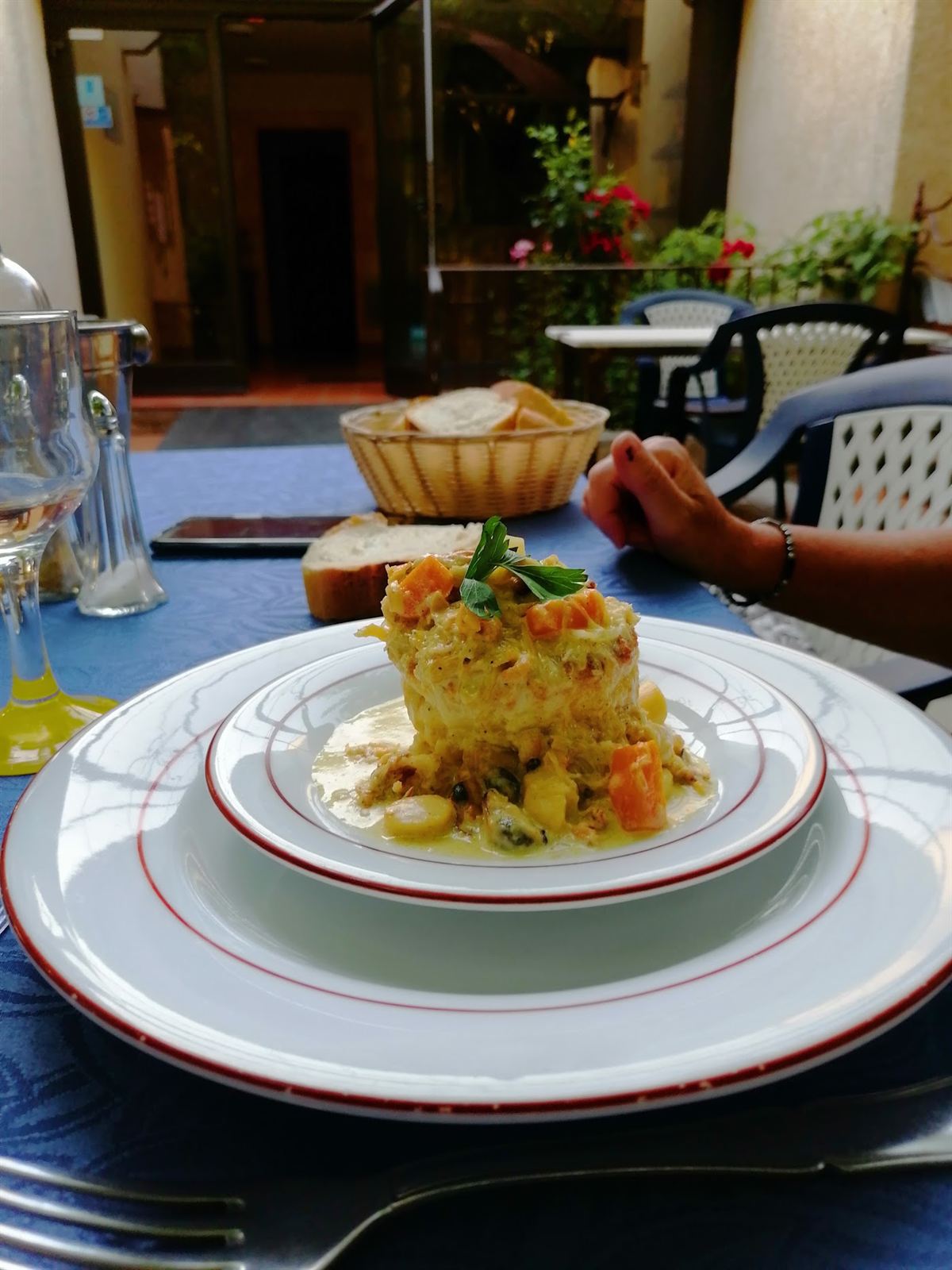 Assiette dressée, brunoise de légumes et pain sur une nappe bleue