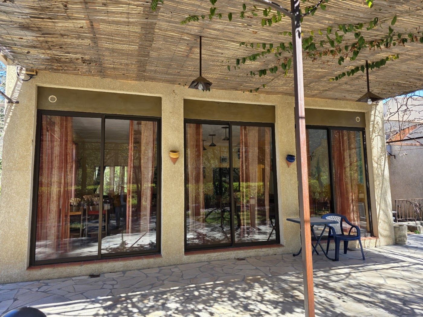Façade ocre du restaurant Le Grand Pré, ouverte sur la terrasse en pierre