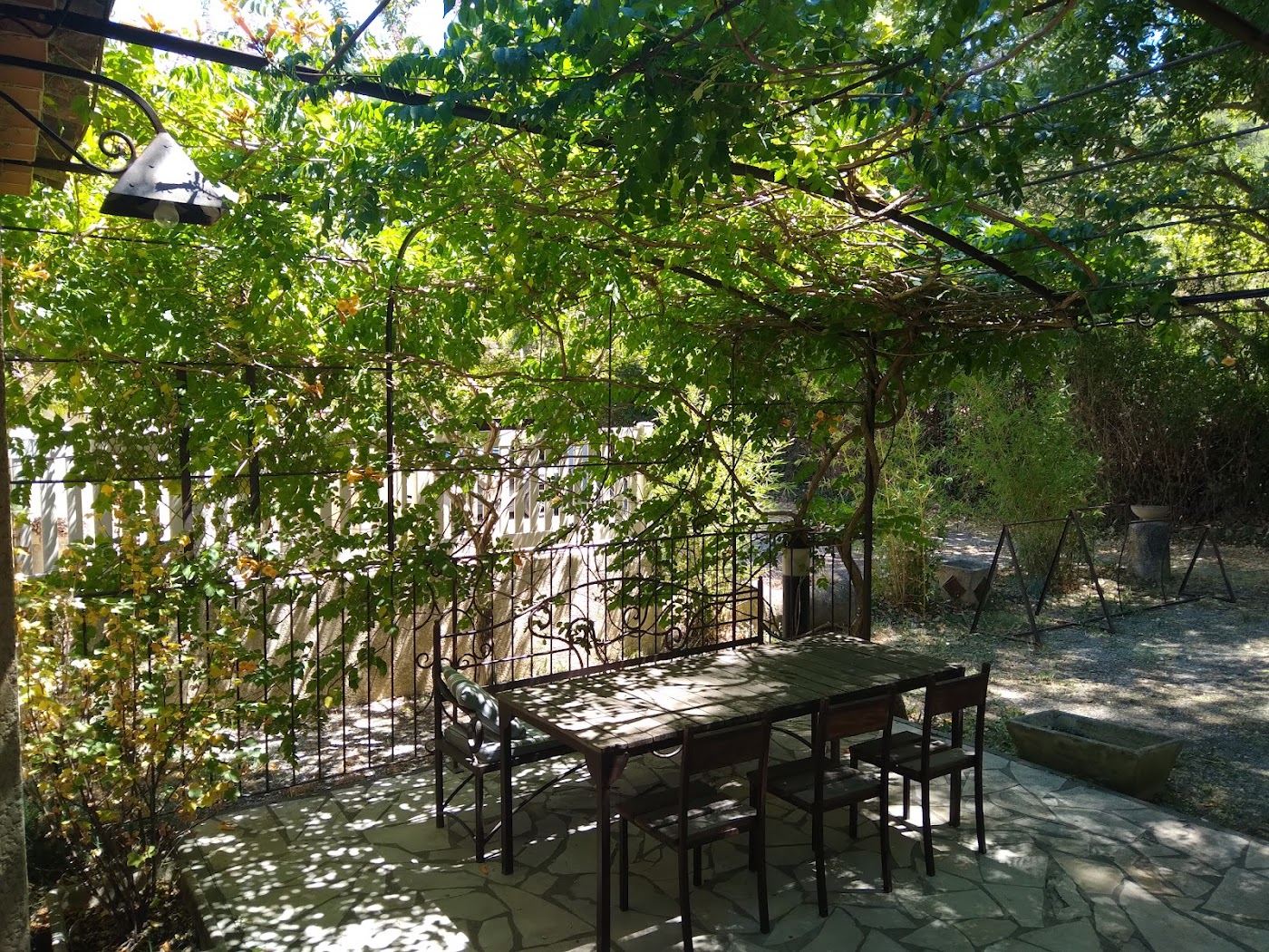 Tables dressées sous la pergola et les feuillages de la terrasse