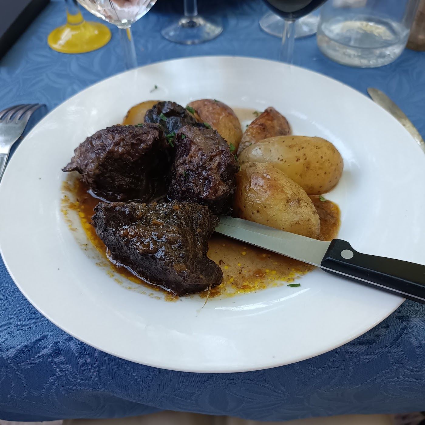 Viande mijotée nappée de sauce, accompagnée de pommes de terre rissolées